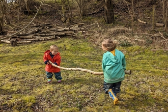 Children in forest carrying a log
