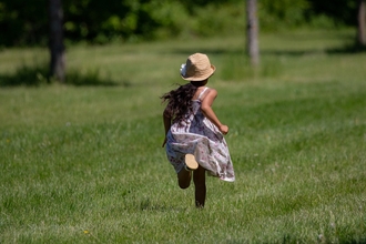 Child in hat running through field