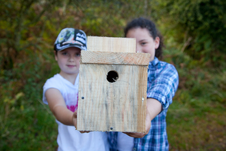 Two children holding a bird box