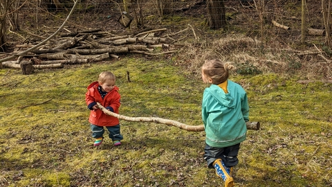 Children in forest carrying a log
